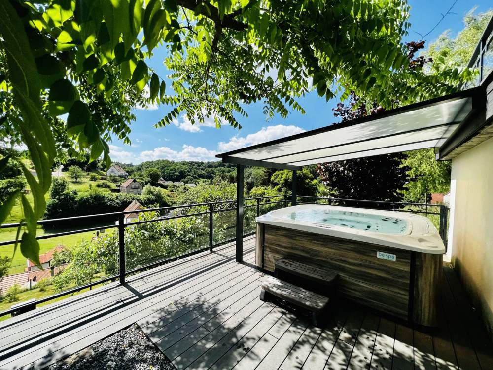 Jacuzzi extérieur du Gîte des Hauts de la Grange sur la terrasse avec vue sur la vallée